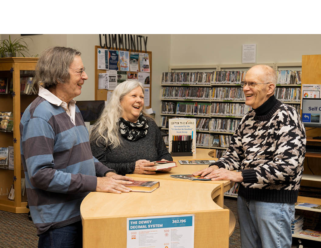 Three adults laughing in conversation in the community area